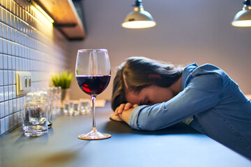 Lonely depressed drinking woman suffering from alcohol addiction abuse with red wine glass alone at...
