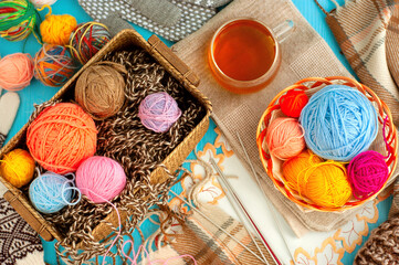 Colorful yarn for knitting. Multi-colored balls of yarn for knitting in a wicker basket. Cozy atmosphere with tea. Knitting as a kind of needlework.
