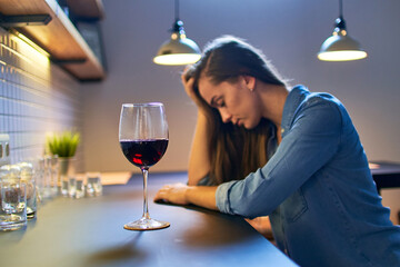 Lonely upset depressed unhappy drinking woman suffering from alcohol addiction abuse with red wine glass alone at home