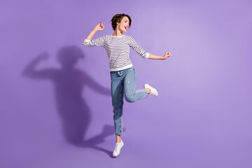 Full length photo of adorable young lady dressed casual clothes dancing looking empty space isolated purple color background