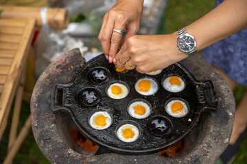 Fried Quail eggs pancake on pothole pan Thai appetizer at street food market Thailand.Thai desserts...