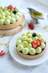 Two Round shortbread pies with green pistachio cream and strawberry jam, close-up. Pistachio tart with cream cheese