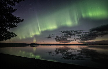 Northern lights dancing over calm lake in Farnebofjarden national park in north of Sweden.