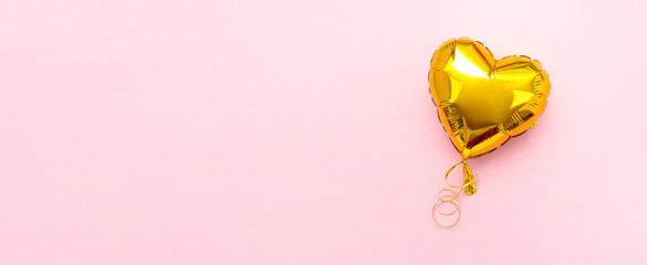 Wide banner with Golden heart foil balloon upper view on pink Valentines Day background. Copyspace.