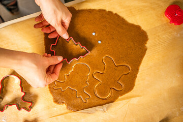 Cutting of gingerbread shapes. A young woman cuts gingerbread shapes on bruna baking paper.