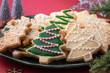 Close up of Christmas sugar cooikes in a plate on red table background.