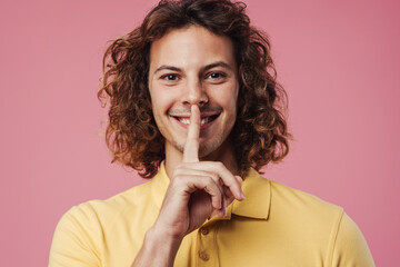 Happy handsome guy smiling and showing silence gesture