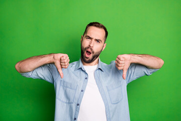 Portrait of impressed sad man wear blue shirt show bad sign open mouth isolated on green color...