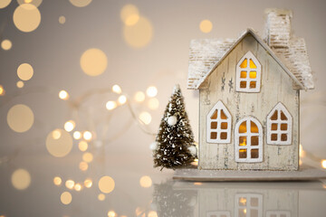 Naklejka premium A toy house on the background of lighted lights. Accessories for Christmas and New Year. Christmas background.