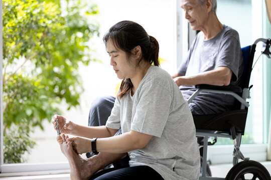 Daughter Hold A Nail Clipper,cutting The Ingrown Nail For Disabled Senior Mother In Wheelchair,asian Woman Help To Cut The Toe Nail For The Old Elderly,feet Nails Care,hygiene Assistance,health Care