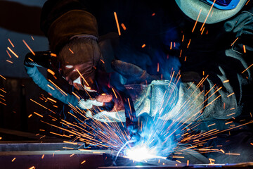 Employee welding steel with sparks using mig mag welder - focus on sparks.