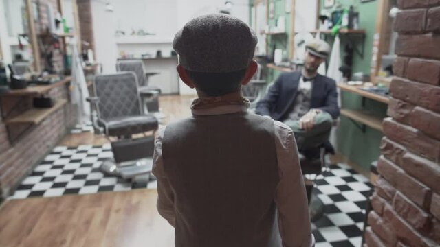 Young stylish gentleman in a cap enters a barbershop