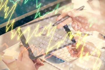 Double exposure of man's hands holding and using a phone and financial chart drawing. Market...