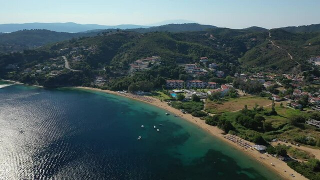 Aerial drone video of famous organised with sun beds and umbrellas sandy beach of Agia Paraskevi in island of Skiathos, Sporades, Greece