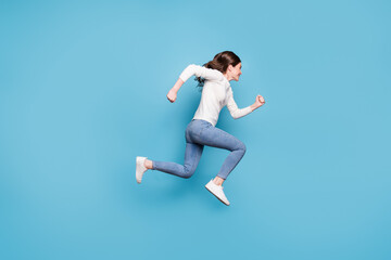 Full length photo of purposeful curly woman dressed white pullover jumping running hands arms fists isolated blue color background