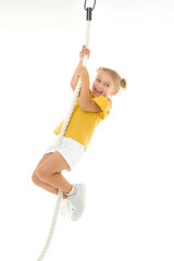 A little girl holds on to the rope with her hands, swinging on it.