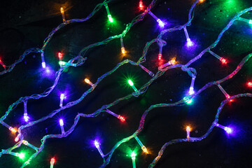 Glowing Christmas tree garland on dark background. Christmas background. Festive background.