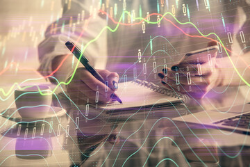 Double exposure of financial graph sketch hologram and woman holding and using a mobile device. Stock exchange concept.