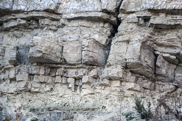 sandy-gypsum cut of the earth in quarry for the extraction of gypsum. Mountain textures of different soil layers with deposits of sand, clay, gypsum, quartz and gypsum ore, after erosion.