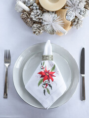 table setting. a beautiful napkin with a red flower you can see a Christmas wreath from above