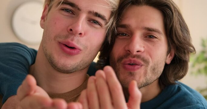 Loving gay couple giving flying kiss at home