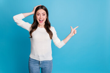 Photo of amazed wavy lady wear white sweater pointing two fingers empty space arm head isolated blue color background