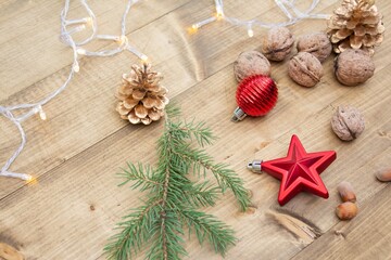 Fototapeta na wymiar Beautiful red Christmas decorations on wooden background. Christmas background with nuts, pine cones, Christmas tree branch, red star and red ball.