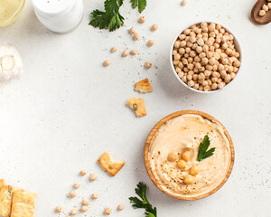 Flatlay Hummus in a wooden plate and raw chickpeas in a bowl. Dishes of chickpeas, a vegetarian dish. Copy space.