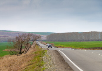 valley, landscape with a road and two cars going into the distance against the background of autumn hills and sky