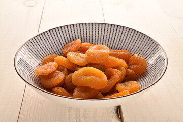 Bright orange natural dried apricots, close-up, on a wooden table.