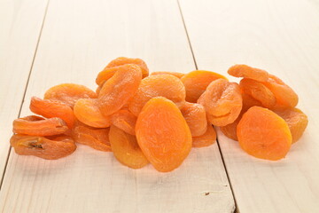 Bright orange natural dried apricots, close-up, on a wooden table.