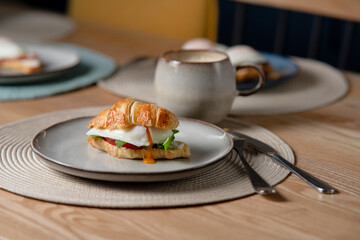 Croissant sandwich with poached egg, avocado and herbs. Healthy breakfast and morning rituals