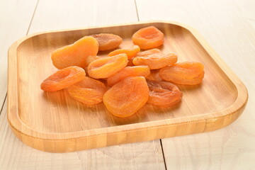 Bright orange natural dried apricots, close-up, on a wooden table.