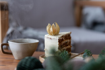 Christmas ornaments, candle, hot punch in ceramic mug and slice of sweet carrot cake. Cozy place on the loggia. Scandinavian mood