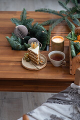 Christmas ornaments, candle, hot punch in ceramic mug and slice of sweet carrot cake. Cozy place on the loggia. Scandinavian mood