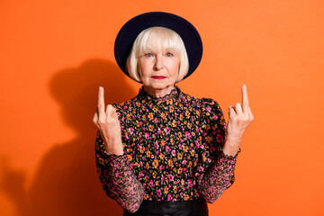 Photo portrait of bad rude granny showing fucking sign gesture in black hat isolated on vibrant...