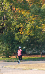 秋の公園でジョギングしている若い女性の姿