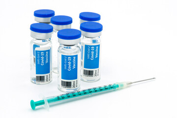 Six Covid-19 vaccination vials and a syringe with white background	
