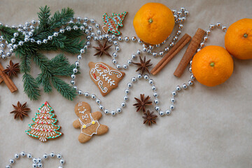 Christmas, New Year gingerbread composition. Christmas card with fur tree branch, tangerine, gingerbread, cinnamon, anise on craft paper background. Place for text, top view