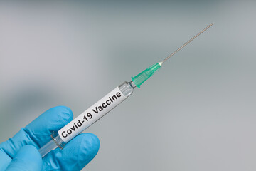 Close up of scientist's or doctor's hand in medical gloves with a syringe containing a Covid-19 serum / vaccine