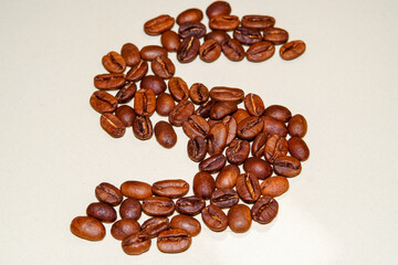Macro view of freshly roasted coffee beans in the shape of a letter "S", extreme close up photo of fresh coffee beans.