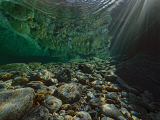 Incoming sunlight and light reflections on rocks underwater 