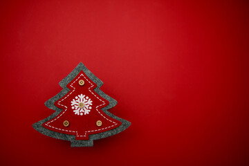 Christmas tree gray with red sewn fabric with a white snowflake in the center and with buttons on a red background. Christmas tree made of fabric on a red background with buttons