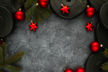 Heavy dumbbells weight plates and Christmas tree branches with decorative baubles ornaments. Healthy lifestyle Holiday season composition, festive flat lay concept with copyspace.
