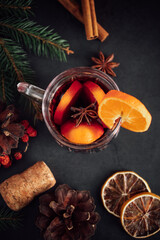 Traditional Christmas warming mulled wine. Hot drink with spices in glass cup on dark background.