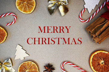 HAPPY NEW YEAR phrase on craft background with candy canes, cinamon, wooden fir trees, and dry oranges. New year concept. Festive concept. Happy new year concept. Background for post card.