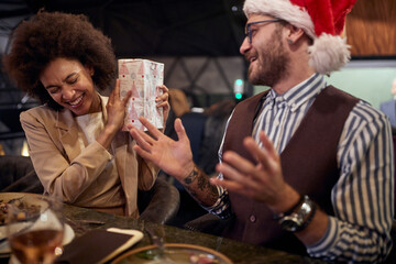 A female colleague excited about New Year present she got from male colleague at company dinner in restaurant. Together, New Year, celebration