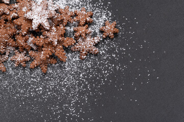 Snowflakes shaped cookies sprinkled with powdered sugar on gray background. Copy space. Homemade baking