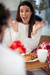 A young girl in the bed surprised by Xmas present she got from boyfriend. Christmas, relationship, love, together
