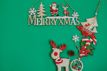 Advent Feast festive Christmas decorations flat lay with text copy space. Top view of overhead seasonal colorful composition figures on green background, with Merry Xmas sign.